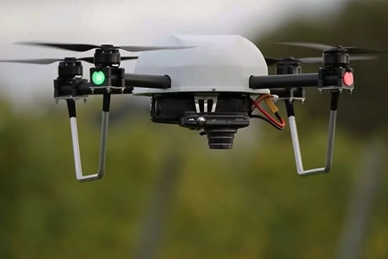 Volumetric Survey Services With Drones at Best Prices in Chennai Quadcopter drone in flight with green and red navigation lights, against a blurred background.